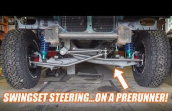 Front suspension system of a prerunner truck with swingset steering, showcasing the undercarriage and various components including coilovers and tires.