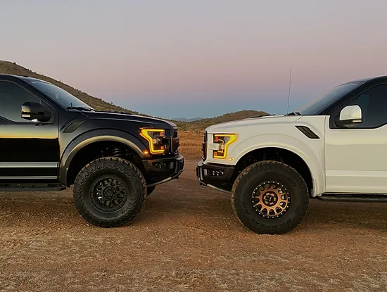 Showing height difference between two ford Raptors, one with Geiser Bros lift kit and one without