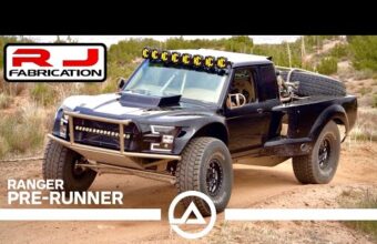 Black Ford Ranger prerunner truck modified for off-road use with large tires, reinforced front bumper, and a roof light bar, parked on a dirt road with desert vegetation in the background, RJ Fabrication logo and text visible.