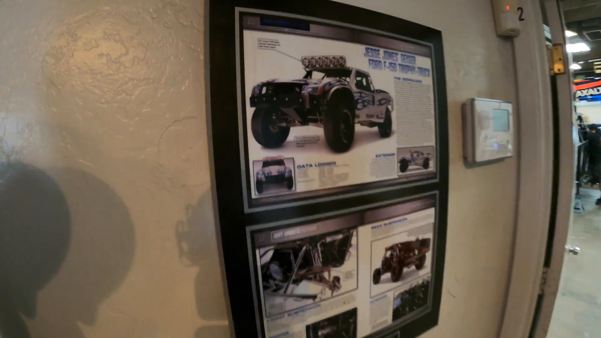 Framed collage on a wall featuring images and text about a modified Ford F-150 trophy truck.