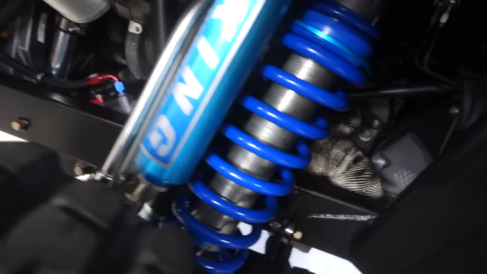 Close-up of a blue coilover suspension system with a shock absorber, possibly part of a vehicle like a Prerunner.