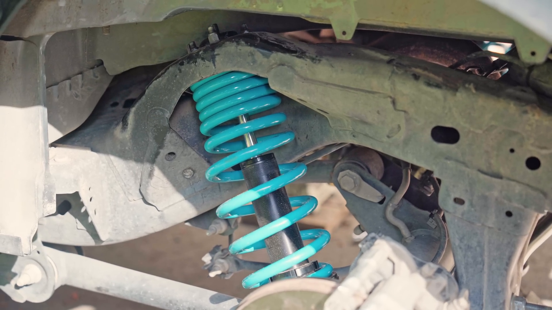 Close-up of a blue suspension coilover on a truck chassis, often used in prerunner vehicles for off-road performance.