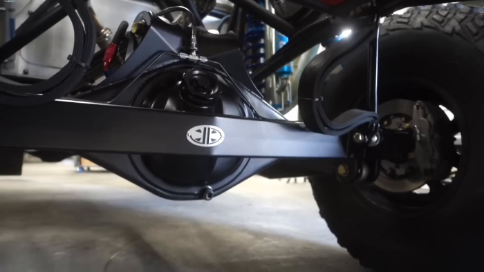 Close-up view of the rear suspension and differential of a Prerunner vehicle with large off-road tires, shock absorbers, and a reinforced axle housing.